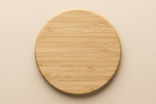 Blank round bamboo wooden coaster plate on a beige background
