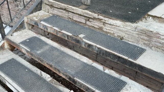 Worn metal steps with antiskid coating, heavy wear, rust, flaking paint and reduced grip on grating treads outdoor urban pickup