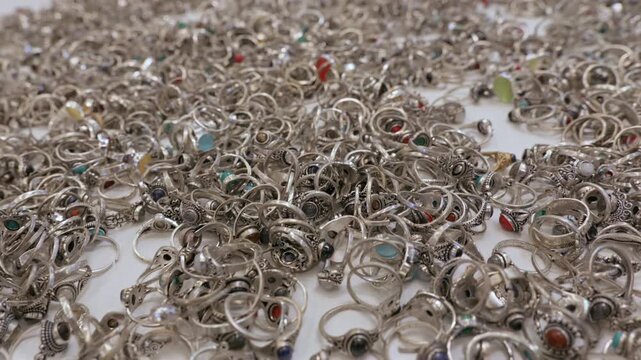 Handcrafted rings with natural gemstones displayed for sale on a white background in an Indian market