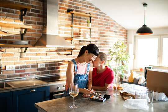 Loving couple eating sushi in modern home kitchen