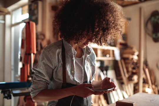 Artisan using smartphone in woodworking studio