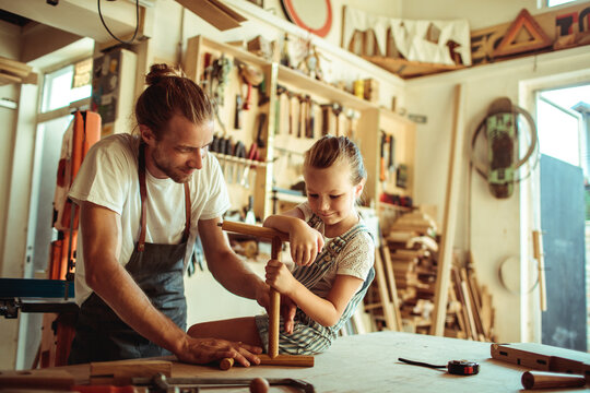 Father teaching daughter woodworking in home workshop