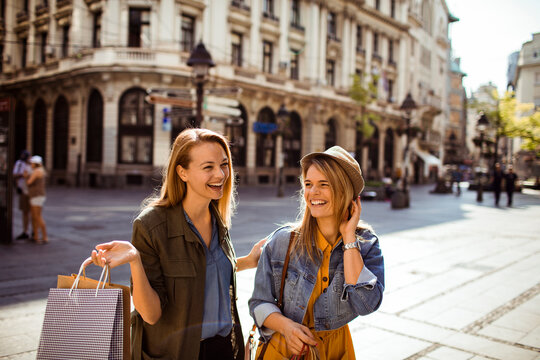 Two friends shopping and laughing on sunny european city street