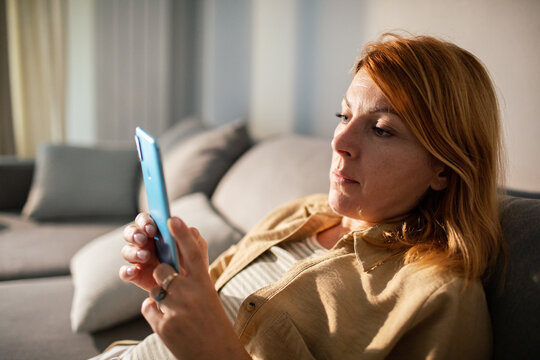 Woman using smartphone on couch at home