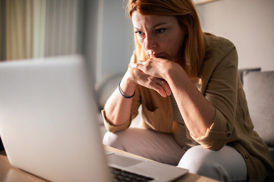 Worried woman looking at laptop at home