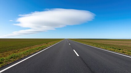 Obraz premium Endless Horizon: An open asphalt road stretches towards the distant horizon under a vast blue sky with a single, elongated cloud. The surrounding landscape is a flat expanse of green fields.
