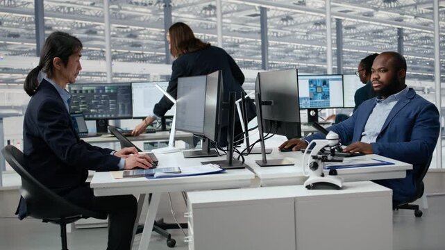 Man examining microchip circuit layouts on monitor in factory R&D office using specialized software tools.
