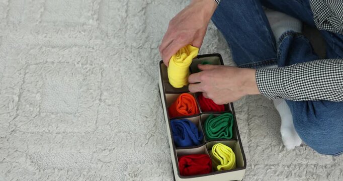 Man putting socks into organizer on floor at home, above view