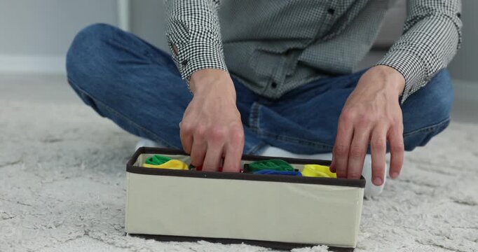 Man putting socks into organizer on floor at home, closeup