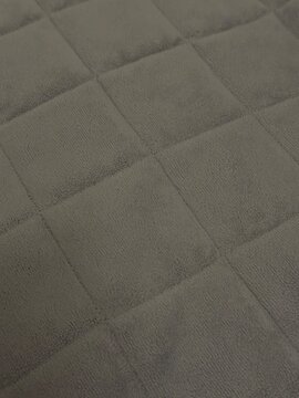 Vertical close up of grey quilted microfiber blanket texture with square pattern background