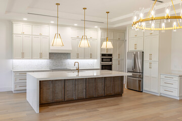 Perspective view of luxury modern kitchen featuring a large central island with waterfall countertop, gold pendant lights, and high-end cabinetry © Andrei Liashchou