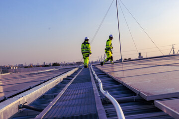 Naklejka premium New technologies and solar panels. The supervisor is checking on solar panels on the rooftop. Male and female electrical engineers working on solar rooftop, sustainable energy.
