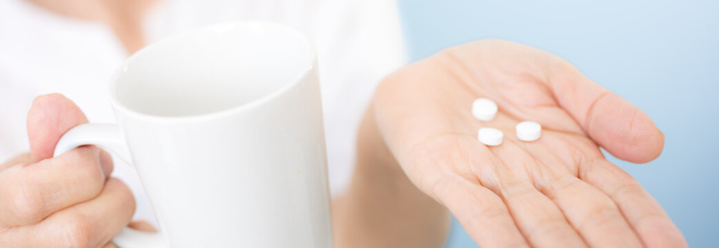 水色背景で薬を飲むグレイヘアの高齢者（シニア）女性　健康管理・服薬・医療・ヘルスケアのイメージ　顔無しのバナー