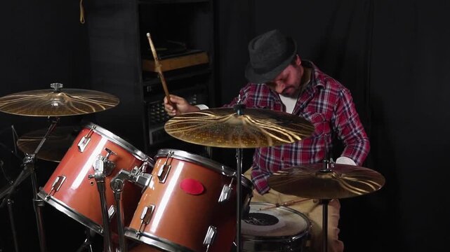 Passionate male musician drumming with drumsticks during an intense studio session