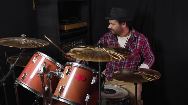 A man is practicing the drums in a recording studio