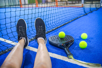 Naklejka premium Point of View of Player Resting Legs Against Net on Blue Padel Court