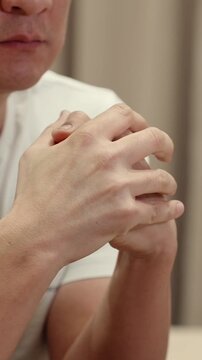 Close up of adult man clasping hands near his face, showing anxiety, prayer, hope, stress, emotional tension, serious decision making and quiet personal reflection indoors.