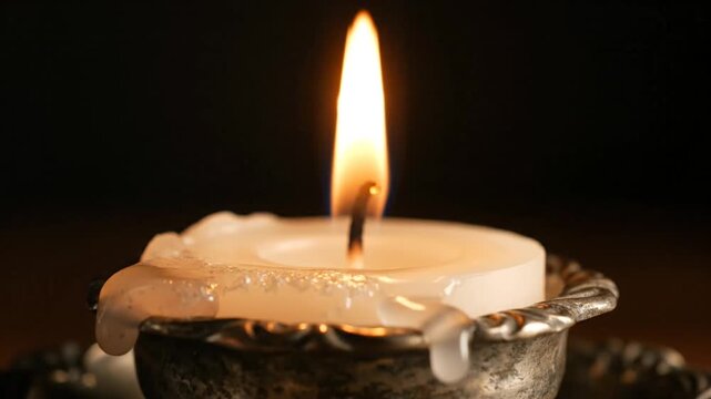 Candle flame with snuffer tool touching wick in darkness