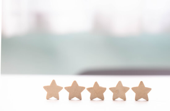 Five star rating review customer feedback satisfaction quality service reputation evaluation wooden star row white table, minimal background, bright light, positive satisfaction concept with copy
