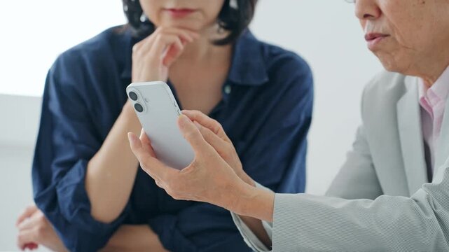 スマホを見る女性とシニア男性