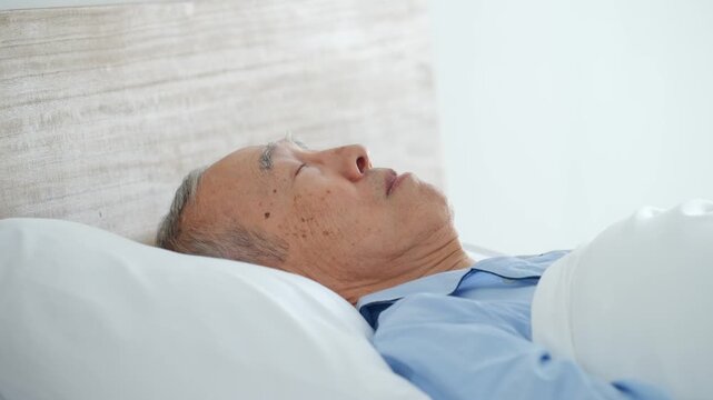 ベッドでぐっすり眠るシニア男性