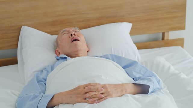 ベッドでイビキをかいて寝るシニア男性