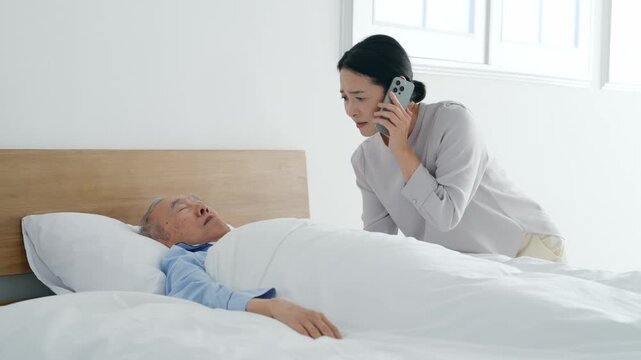 昏睡するシニア男性とスマホで電話する女性