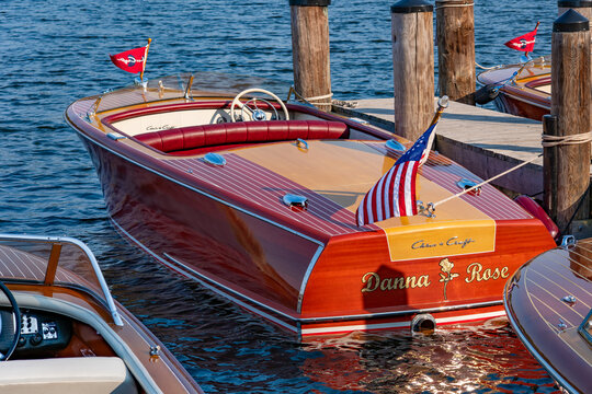 LAKE SHORE, MN - 12 SEP 2024: Classic Chris-Craft wooden speedboat named Danna Rose with mahogany hull and American flag moored at a dock during a vintage boat show on a Minnesota lake.