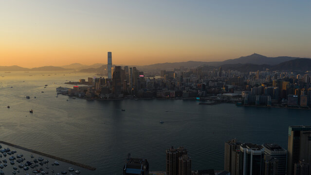 Hong Kong - 14 February 2026: Aerial view of the skyline and Victoria Harbour with the International Commerce Centre ICC tower and mountains during sunset.