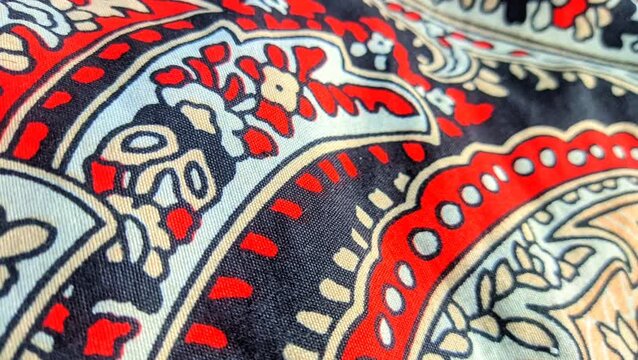 Traditional paisley batik fabric pattern with intricate floral details and red accents close up video

