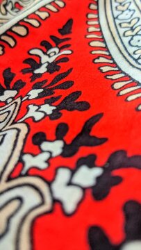 Traditional paisley batik fabric pattern with intricate floral details and red accents close up video
