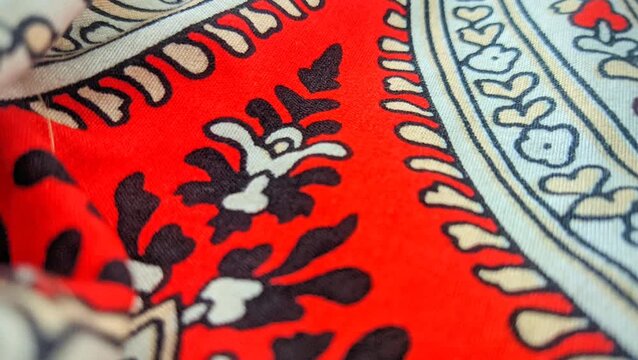 Traditional paisley batik fabric pattern with intricate floral details and red accents close up video
