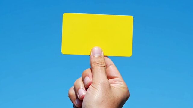 Hand holding a yellow sticky note against a blue background.