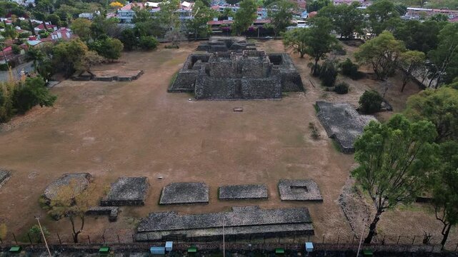 Aerial drone moves gently around the Teopanzolco archaeological zone in Cuernavaca, Morelos, revealing the ancient Tlahuica pyramid ruins and ceremonial structures surrounded by lush greenery