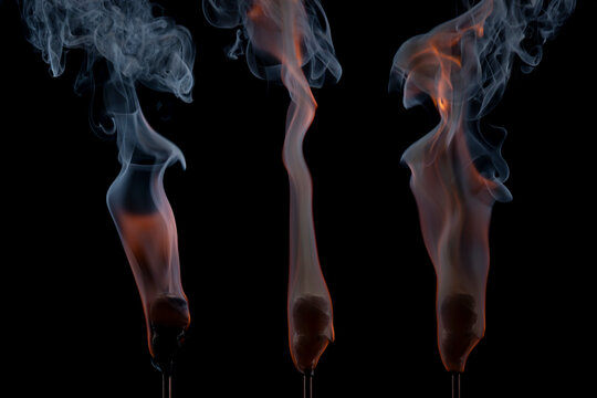 Active torches with hot smoldering embers emitting dynamic wisps of smoke against a dark backdrop. Concept of burning energy, heat, and power.