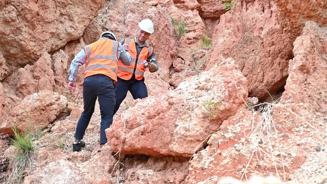 Two expert geologists are working together to examine the soil layers near the cliff.