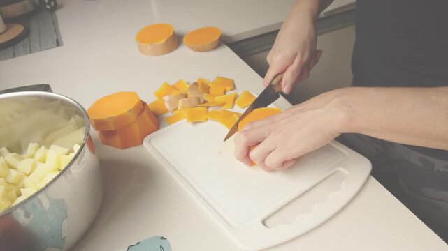 Woman cutting butternut squash on a cutting board