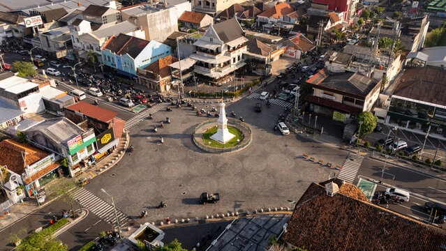 Yogyakarta, Indonesia - 05 June 2026: Aerial view of Tugu Yogyakarta monument at a busy city intersection with motorcycles and historic buildings under bright daylight.