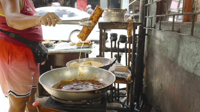 Filipino Vendor Taking Cooked Banana Cue from Food Display Case