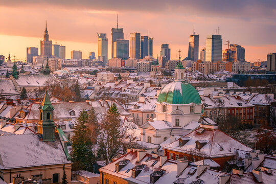 Warsaw, Poland - 04 January 2026: Aerial view of the Church of St Casimir and snow-covered rooftops of the Old Town with the modern city skyline at sunset in Warsaw, Poland.