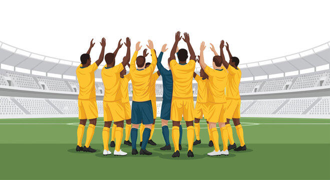 Soccer team members in yellow jerseys stand in a huddle on a grass field clapping their hands inside a large empty stadium arena.