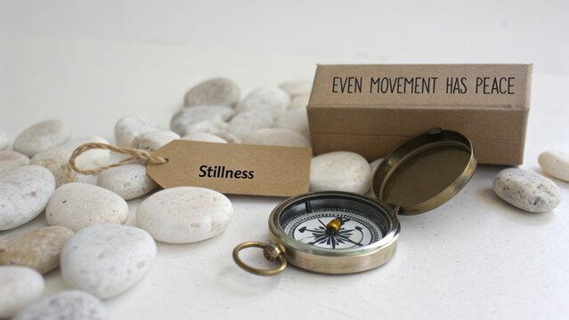 Vintage Compass on Pebbles with Inspirational Quote About Peace and Stillness in a Serene Environment