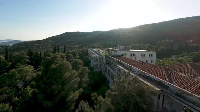 Aerial Fpv Drone Shot, Close up of Sanatorio Hospital Building in Kavala Greece, Abandoned Landmark in Greek Countryside, Backlit Footage