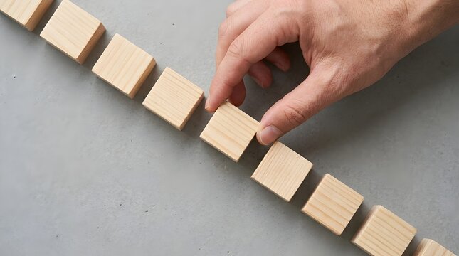 Strategic hand meticulously placing a wooden cornerstone to complete the bridge of professional growth