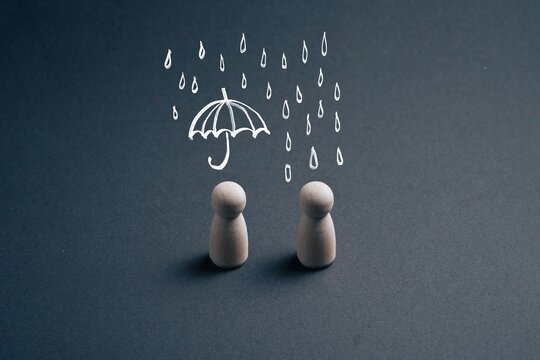 Two wooden figures stand under falling rain. Two wooden figures stand under falling rain
