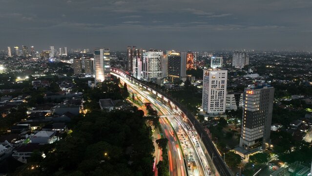 Cilandak, Indonesia - 10 April 2026: Aerial view of the Lebak Bulus area at night with light trails from traffic on the highway, modern skyscrapers, and the illuminated urban skyline.