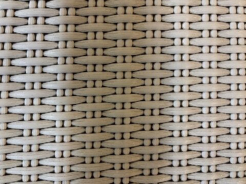 Light beige synthetic rattan wicker texture background with repetitive woven pattern.