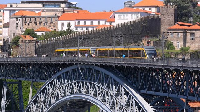 Metro train crossing famous Dom Luis I Bridge in Porto at sunset