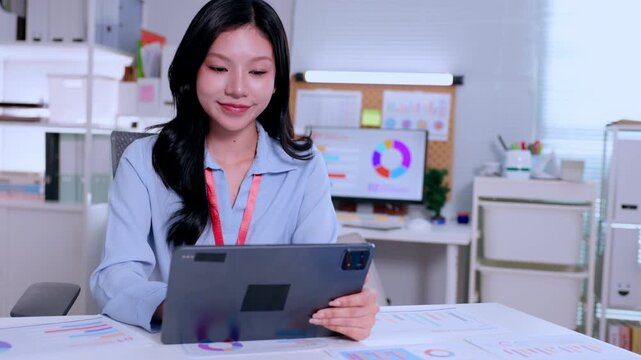 Young professional female using tablet at office desk with chart report document, calm focused workplace technology for business analysis presentation modern data concept