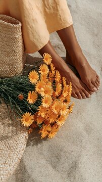 Close-up of bare feet beside orange flowers on textured surface